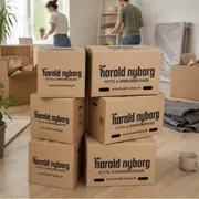 Stak af brune flytte- og opbevaringskasser med håndtag, mærket 'Harald Nyborg.' Kasserne er robuste, rektangulære og velegnede til flytning eller opbevaring af husholdningsgenstande.