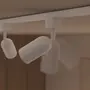 Hvid justerbar loftsskinne med cylindriske spotlys, monteret på en lige skinne. Spotlysene kan drejes og vinkles for fleksibel belysning.