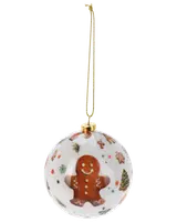 Rund julgranskula med pepparkaksgubbe, festliga motiv och gyllene snöre. Vit bakgrund med färgglada julmotiv som granar, snöflingor och godis. Blank yta.