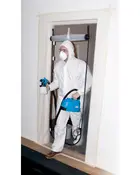 Engangs hvid beskyttelsesdragt med hætte, båret af person. Inkluderer ansigtsmaske og beskyttelsesbriller. Velegnet til maling, rengøring eller farlige miljøer. Let, heldækkende, elastiske manchetter.