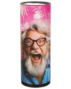 Høj cylinderformet lys med farverigt omslag, der viser fyrværkeri og en person med gråt hår og skæg iført blå skjorte. Ansigtet er sløret for privatliv.