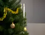 Kunstigt juletræ med guldfarvet guirlande, guldkugler og et hvidt LED-lysornament fastgjort på en gren. Lyset har varm glødende flammeeffekt. Enkel julepynt.