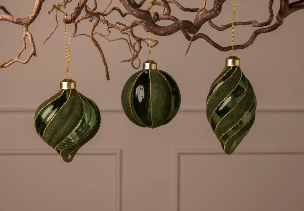 Set med tre gröna julgranskulor i glas med gulddetaljer, två med vridet mönster och en rund, alla med guldfäste och upphängningsögla.