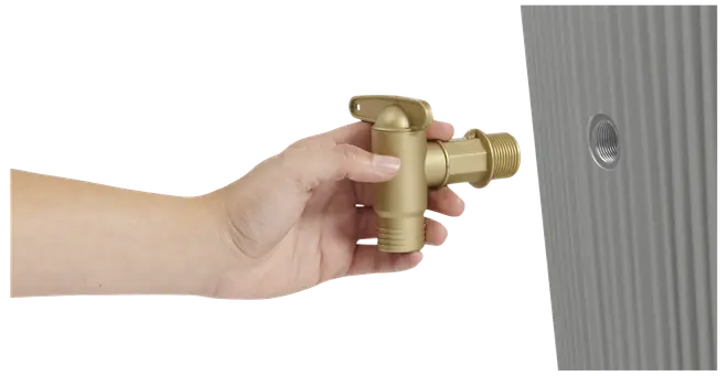 En hånd holder en udendørs messinghane med gevind, klar til montering på et vægmonteret rør. Hanen har et greb for nem betjening.