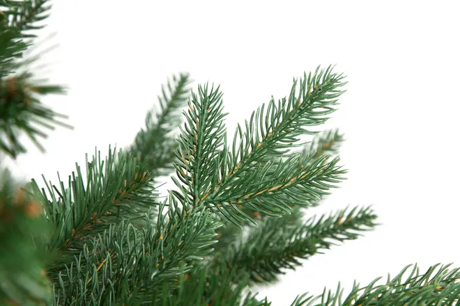 Kunstig fyrregrens med tætte, grønne plastiknåle og brune stængler. Velegnet til juledekoration eller juletræ. Naturtro udseende. Hvid baggrund.