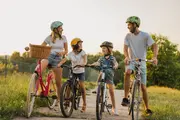 Fire cykler i forskellige størrelser, inklusive en lyserød cykel med frontkurv. Alle har lige styr, solide stel og sikkerhedshjelme. Velegnet til familieudflugter på cykel.