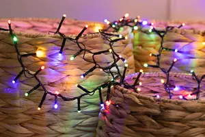 A string of small, round LED lights in multiple colors (red, green, blue, yellow, and purple) is draped over woven, natural-colored baskets. The lights are attached to a black wire, and the baskets have a tightly woven, textured surface. The lights are evenly spaced and emit a soft, festive glow.