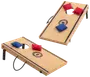 Sæt med to cornhole-brætter i træ med sorte striber og logo, inkluderer røde og blå ærteposer. Brætterne har foldbare ben og bærehåndtag for nem transport.
