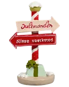 Juledekorationsfigur med rød-hvid stribet stolpe, to retningsskilte, sne detaljer og en grøn gave ved basen. Skiltene viser 'Julemanden' og 'Nisse værksted'.