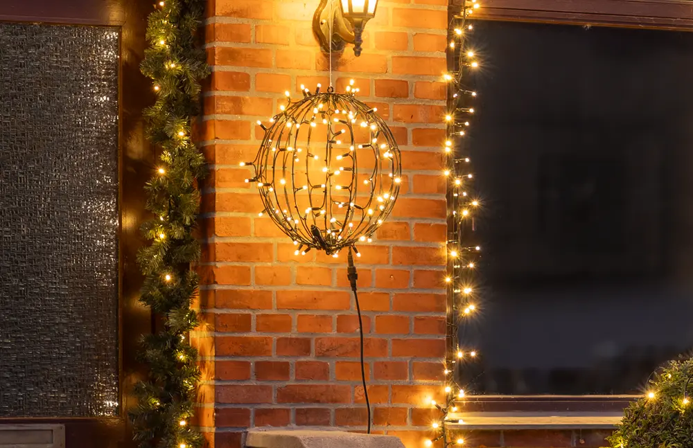 Utomhus dekorativ ljussfär med varmvita LED-ljusslingor, avsedd för upphängning. Passar för festlig eller säsongsbetonad dekoration, väderbeständig, med synlig svart sladd.