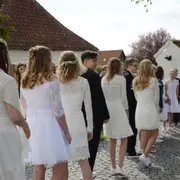 Hvid knælang kjole med blondeærmer og overdel, markeret talje og vid nederdel. Velegnet til formelle lejligheder som konfirmation. Bæres med hvide sko.