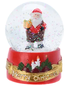 Julig snöglob med tomtefigur som håller ett paket. Glitter inuti. Röd bas dekorerad med ljus, grönska och ett gyllene "Merry Christmas"-band.