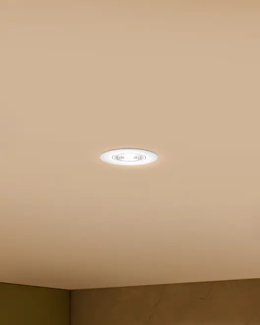 Rund indbygget LED-loftlampe med hvid kant, monteret i beige loft. Giver fokuseret, energieffektivt lys, ideel til moderne og minimalistiske rum.