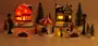 Miniatyr-julby med två upplysta hus, karusell, figurer, lyktstolpar och snötäckta träd. Detaljerad, festlig dekoration för jul- eller modellscener.