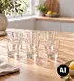 Seks klare glaskopper arrangeret på et lyst træbord i et lyst køkken. - Billedet er skabt med AI