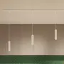 Moderne pendellampe med tre slanke, cylindriske hvide lamper hængende fra loftsskinne. Minimalistisk design, justerbare ledninger, velegnet til køkken eller spisestue.