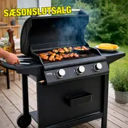 Sort gasgrill med tre kontrolknapper, sidehylder og hjul. Grillen er åben, mad grilles på risten. Tallerken med majs på sidehylde. Udendørs miljø.