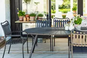 Sort metal udendørs spisebordssæt med rundt bord og fire lamelstole. Moderne design, vejrbestandig finish, egnet til terrasse eller have. Bordpladen har radiært mønster.