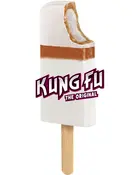Rektangulær is med hvid bund, karamelbrun lag og træpind. En bid er taget af toppen. "Kung Fu The Original" tekst på forsiden.