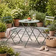 Grønt cafésæt med rundt bord og to klapstole på en træterrasse i haven