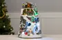 Oplyst julelandsbydekoration med snedækket bjerg, fyrretræer, hytter, skiløbere og farverige LED-lys. Detaljeret vinterscene, ideel til bord- eller pejseudsmykning i juletiden.