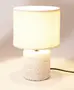 Moderne bordlampe med cylindrisk, hvid stenbase og rund, cremefarvet stofskærm. Har sort ledning. Velegnet til soveværelser eller stuer.