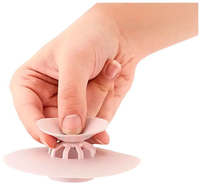 Hand trycker på en vit silikonavloppspropp med slitsad botten och sugkoppsdesign.