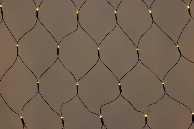 Netformede lyskæder med varme hvide LED-pærer, arrangeret i diamantmønster. Perfekt til dekoration af vægge, vinduer eller udendørs områder. Sort ledning passer til mørke baggrunde.