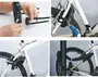 Bildset som visar ett svart cykellås med två justerbara armar, nyckellås och skyddshölje, demonstrerat på en vit cykel för att låsa ram och hjul vid en stolpe.