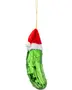 Grønt glasagurk juleornament med knopper, iført rød og hvid nissehue, hængende i en guldsnor. Sjov og festlig juledekoration.