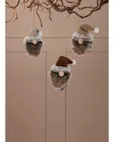 Set med tre mjuka tomteprydnader med fuskpäls, runda näsor och stickade mössor i beige, brunt och sand. Hängs i snöre, perfekt för juldekoration.