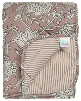 Vatteret tæppe med brun og hvidt blomsterprint på den ene side, beige og hvide striber på bagsiden, blød tekstur og synligt plejemærke. Velegnet til seng eller dekoration.