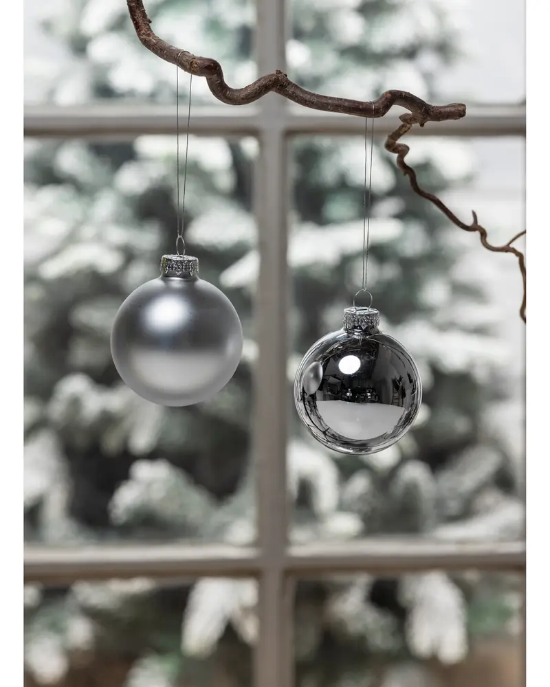 Set med två julgranskulor, en matt silver och en blank krom, båda runda med silverfäste och upphängning. Elegant, minimalistisk design för festlig dekoration.