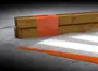 Klar plastfolie med orange tape, vist fastgjort omkring træbjælker. Perfekt til afdækning, beskyttelse eller samling af materialer under byggeri, maling eller opbevaring.