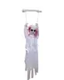 Hängande Halloween-dekoration av spökflicka i trasig vit klänning med rosa hår, sittande på en gunga upphängd i kedjor från en vit stång.