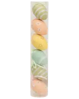 Sæt med seks dekorative påskeæg i pastelfarver med striber og blomster, pakket i et klart plastikrør. Hvert æg har et bånd til ophængning.