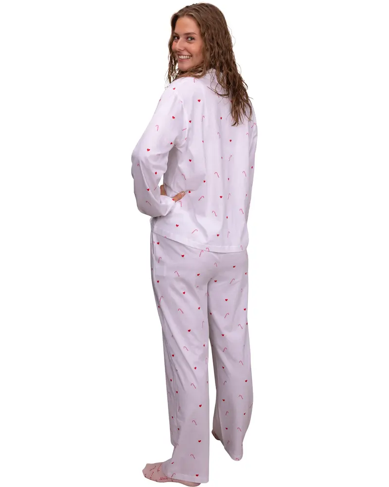 Vitt pyjamas-set med långärmad överdel och byxor, dekorerat med små röda polkagrisar. Avslappnad passform, knappar på toppen, ansiktet är inte synligt.