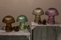 Fyra svampformade bordslampor i räfflat glas, färgerna bärnsten, grön, guld och lila, med inbyggda LED-lampor, dekorativa kottar och rustika träytor.