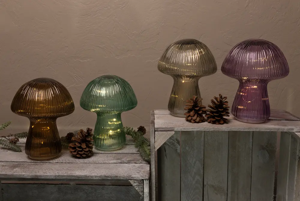 Fyra svampformade bordslampor i räfflat glas, färgerna bärnsten, grön, guld och lila, med inbyggda LED-lampor, dekorativa kottar och rustika träytor.
