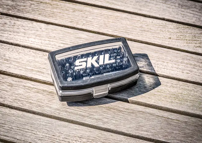 Kompakt SKIL-märkt plastlåda med olika skruvbits, synliga genom ett genomskinligt lock med säker låsning, perfekt för gör-det-själv och reparationer.