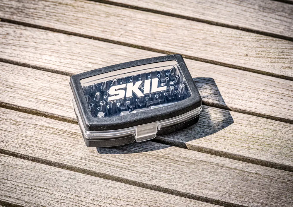 Kompakt SKIL-märkt plastlåda med olika skruvbits, synliga genom ett genomskinligt lock med säker låsning, perfekt för gör-det-själv och reparationer.