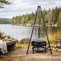 Utomhus svart metallgrill med trebensstativ, hängande rund grillgaller justerbart med kedjor, ovanför eldfat och nedre hylla. Perfekt för lägereldsmatlagning och grillning.