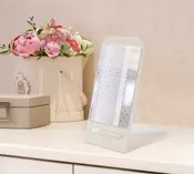 Rektangulært bordsspejl med hvid ramme og foldbart stativ. Moderne og let design, perfekt til makeup eller grooming på kommode eller skrivebord.