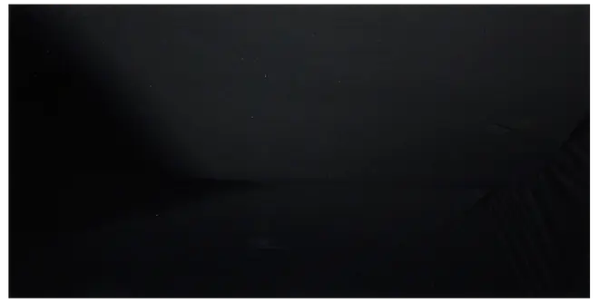 Svart rektangulär vadderad madrass eller kudde med slätt tyg, svaga veck och sydda kanter.