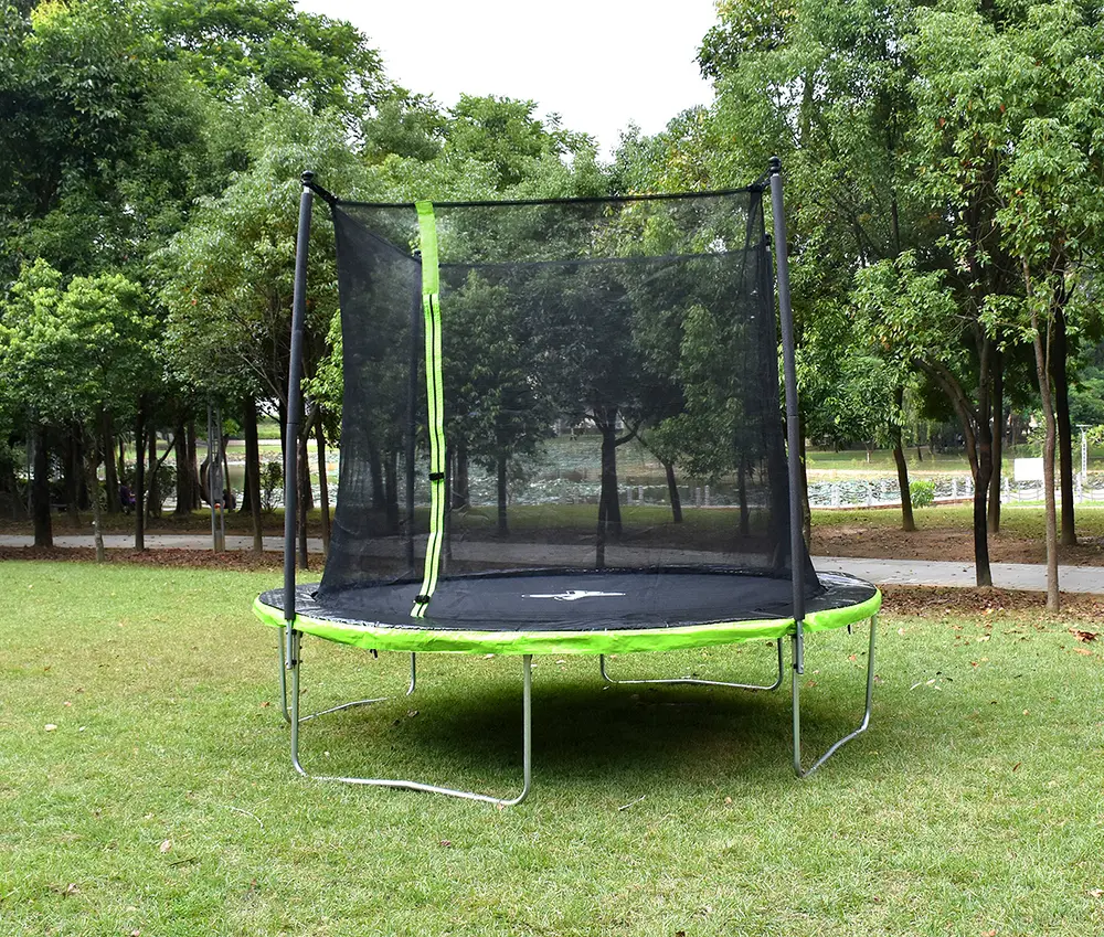 Rund studsmatta för utomhusbruk med grön kant, säkerhetsnät och dragkedjeingång. Metallben, passar barn och vuxna, placerad på gräs i trädgård.