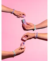 Set med pastellfärgade pilleraskar hålls av händer med flätade tygarmband mot rosa bakgrund. Varje ask har fack för daglig medicinförvaring och enkel åtkomst.