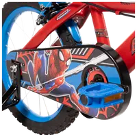 Barncykel med röd ram, blå hjul och kedjeskydd med färggrafik av Spider-Man. Utrustad med blå pedaler och stödhjul för extra stabilitet.