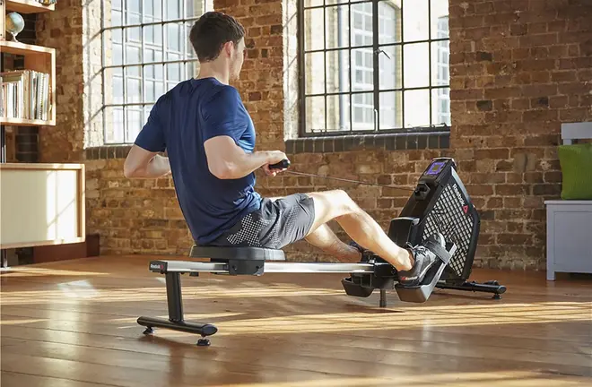 Moderne romaskine med digital skærm, polstret sæde og justerbare fodstøtter. Velegnet til hjemmetræning og helkropstræning. Robust metalramme og glidende skinne.