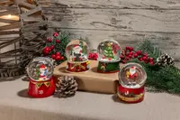 Fyra juliga snöglober med tomte, snögubbe och julgran, alla med röda och gröna baser, perfekta som dekoration eller present till julen.