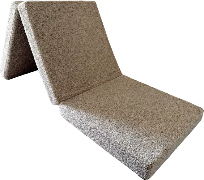 Beige tekstureret foldestol til gulv med polstret sæde og ryglæn, designet som en bærbar loungemåtte.